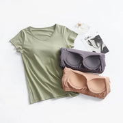 Light green built-in bra tee laid flat beside two strapless bras it replaces