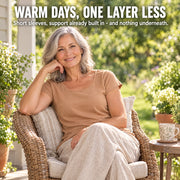 Woman in her sixties relaxing on a sunlit porch in the Maddietanks built-in bra short-sleeve tee in caramel, with short sleeves and support built in